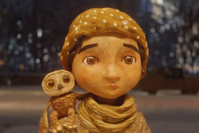 A stop animation still of a little boy in a scarf and and hat with a small owl on his shoulder from the Alfonso Cuaron short film 