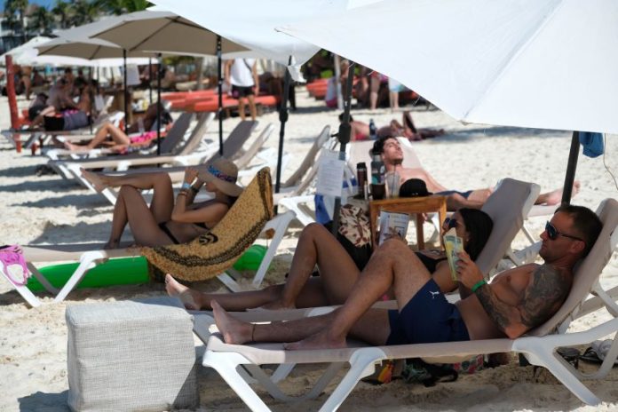 International tourists lay in a row on a sunny Cancún beach