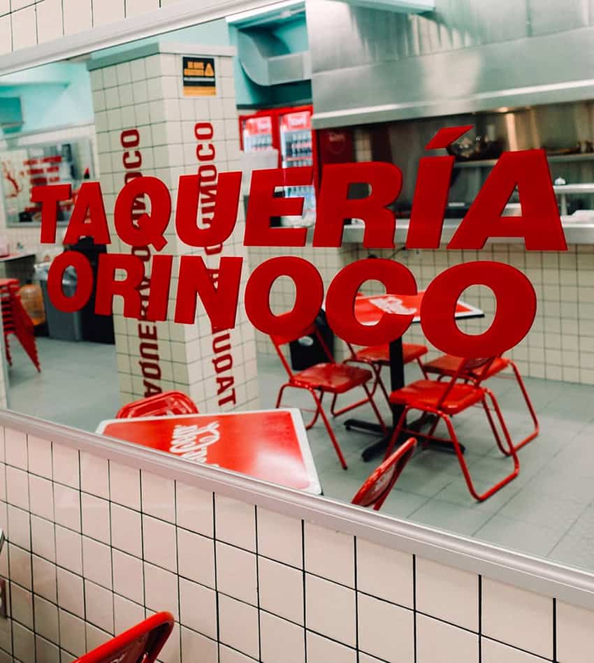 A mirror reads "Taquería Orinoco" in a red and white taco restaurant