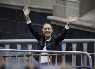 Claudia Shienbaum waves her hands in the air to crowds in Mexico City's Zocalo behind metal security barriers