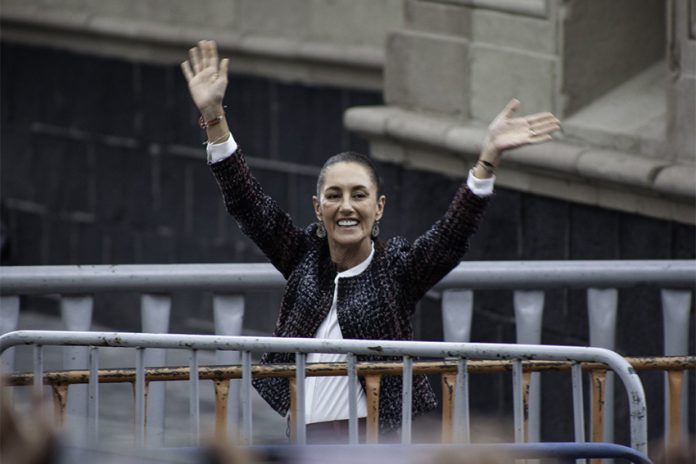 Claudia Shienbaum waves her hands in the air to crowds in Mexico City's Zocalo behind metal security barriers