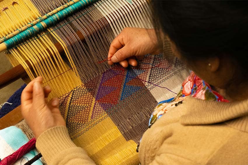 Chiapas woman making yellow woven textiles on a hand loom