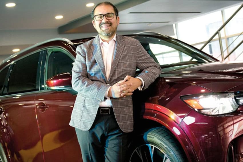 Mazda Mexico Director Miguel Barbeyto standing in front of a red Mazda car in a showroom, smiling.