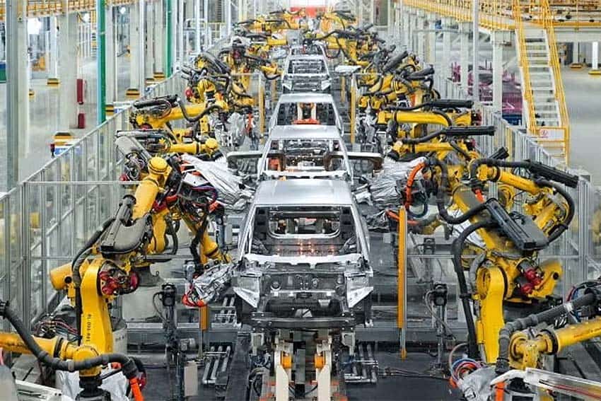 A line of BYD car frames on an assembly line featuring robotic arms on either side