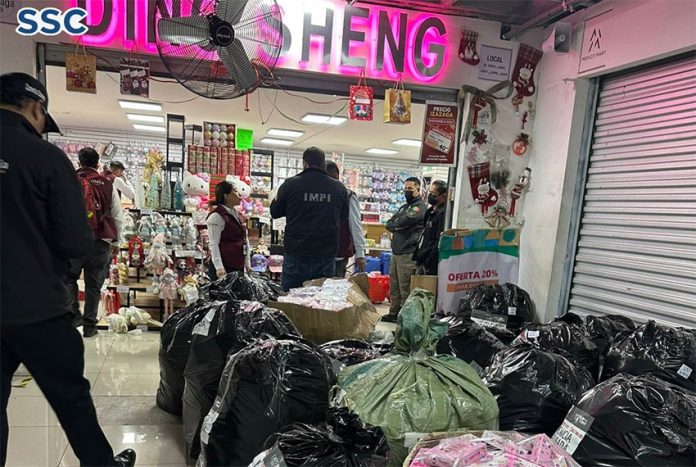 officials gather black plastic bags of counterfeit Chinese products outside a store in Mexico City