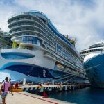 A massive cruise ship towers over a dock in Cozumel, Mexico while passengers cue to board