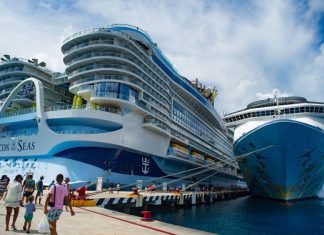 A massive cruise ship towers over a dock in Cozumel, Mexico while passengers cue to board