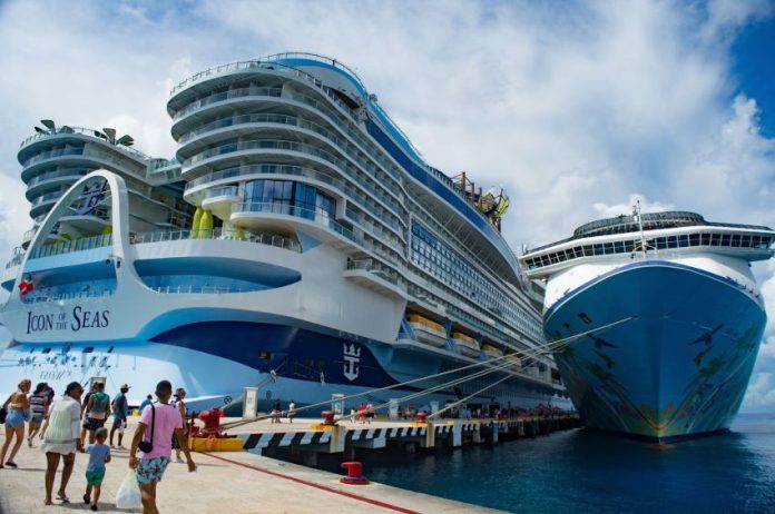 A massive cruise ship towers over a dock in Cozumel, Mexico while passengers cue to board