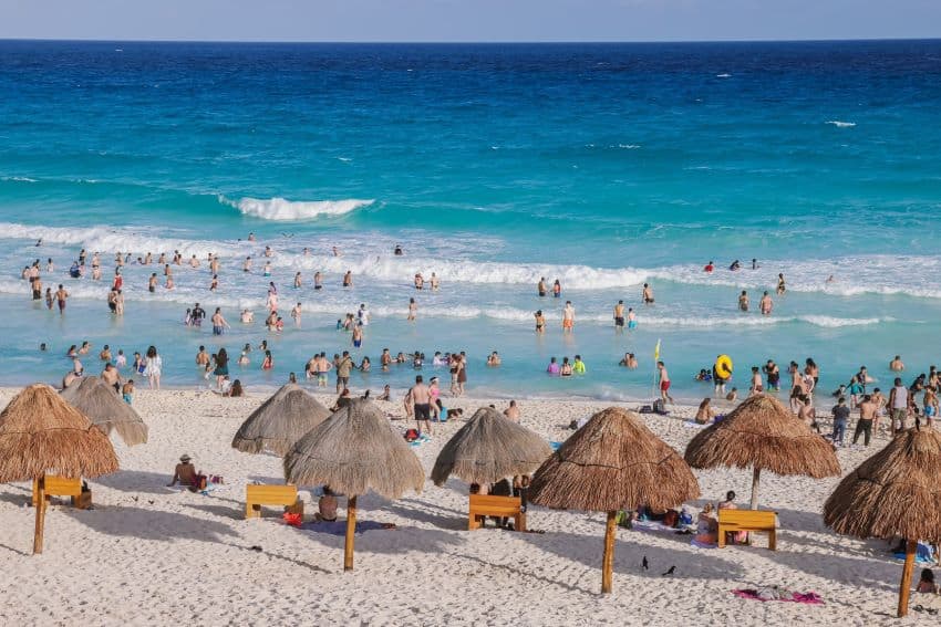 People enjoy the sand and sea on the beach in Tulum