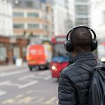 A man listens to headphones in a city, to illustrate the best Mexican msuic and podcasts of 2024