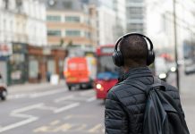 A man listens to headphones in a city, to illustrate the best Mexican msuic and podcasts of 2024