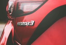 Closeup of the back of a red Mazda car with the Mazda 3 logo on it .