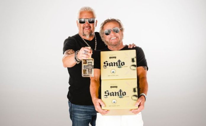 Celebrity chef Guy Fieri, left, and rocker Sammy Hagar, right, holding boxes and a bottle of their brand of tequila, Santo as they pose for a publicity photo