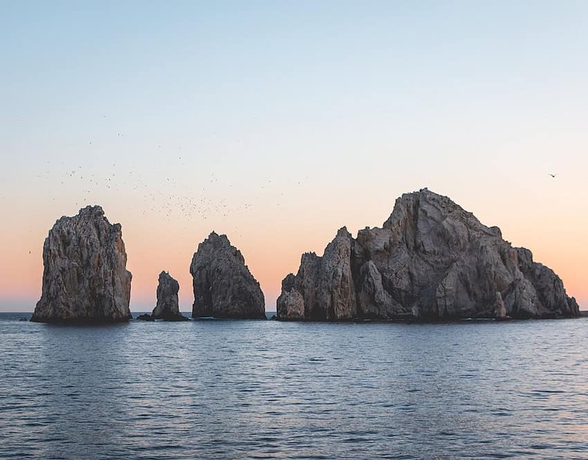 A photograph of the rock formations next to the famous Arch during sunset.