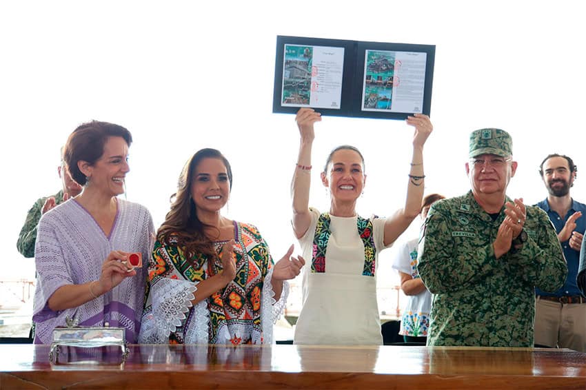 Sheinbaum holds up documents related to the Maya Train to celebrate its completion, surrounded by military and Quintana Roo state officials.