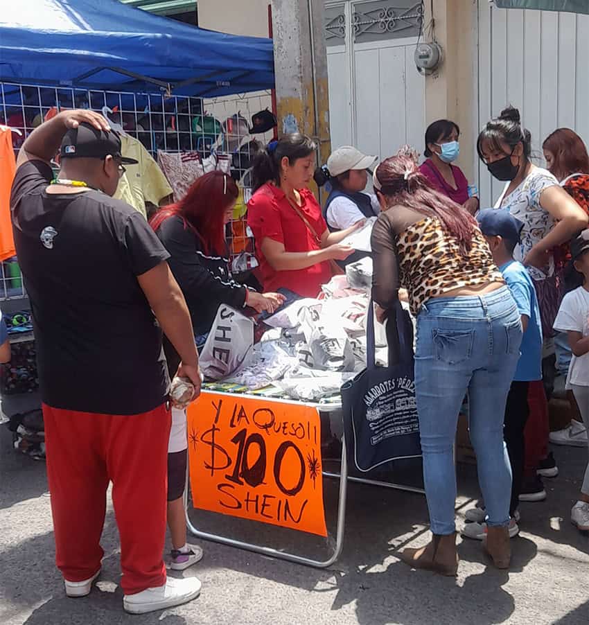 Mexican women, children and a man gather around a market stand selling clothing from the Chinese e-commerce site Shein