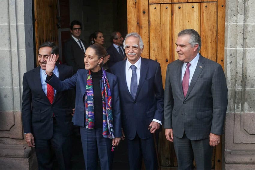 Sheinbaum comes out of a building with older men in suits after a meeting with business leaders in Mexico City