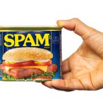 A hand holds a can of spam