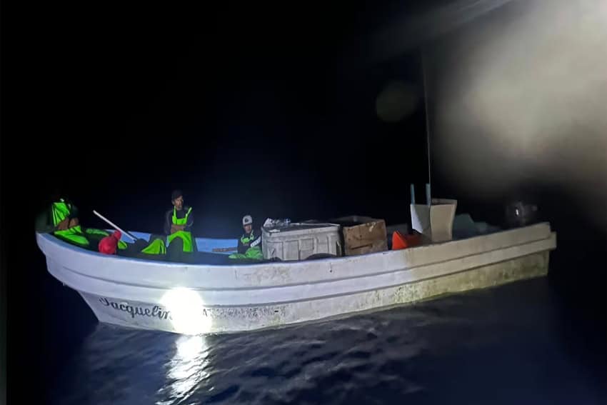 Men in a small motorized fishing boat that bears the name "Jacqueline" painted in cursive on it.