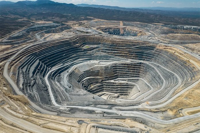 An large open-pit mine in an arid area with mountains in the background